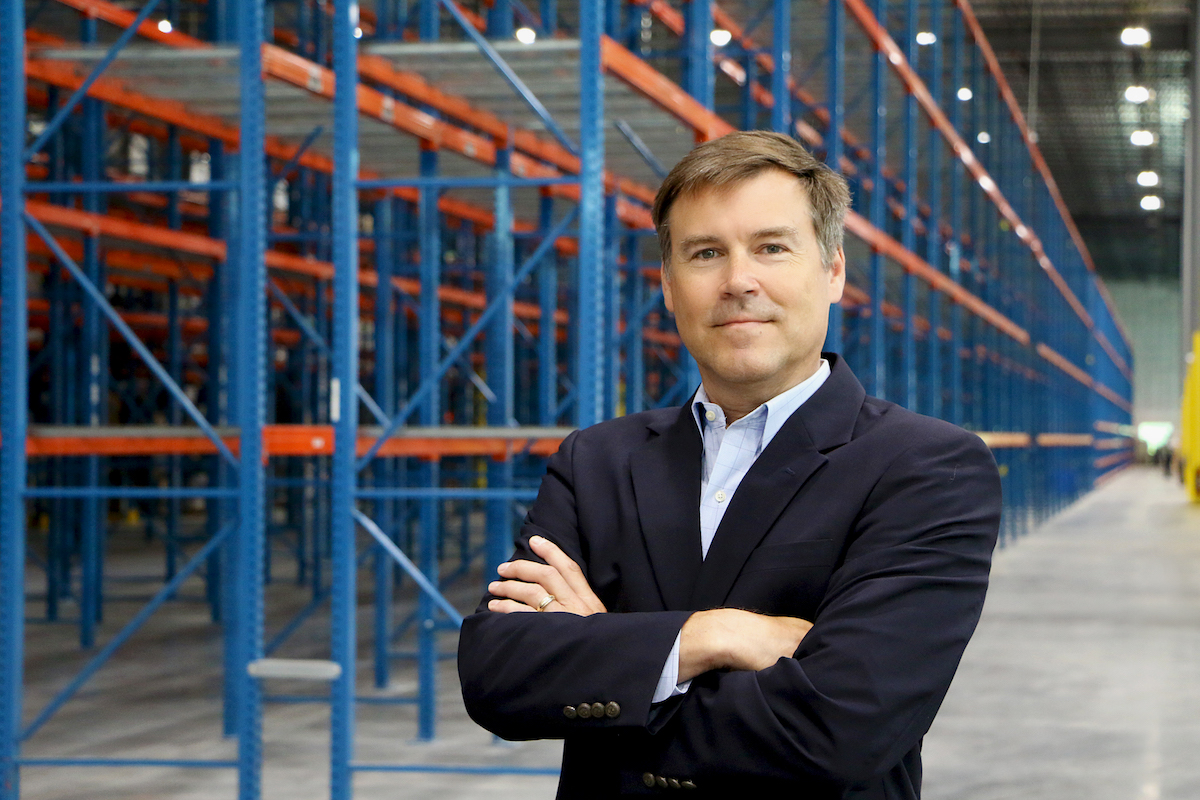 David R stands with crossed arms in a Distribution Management warehouse