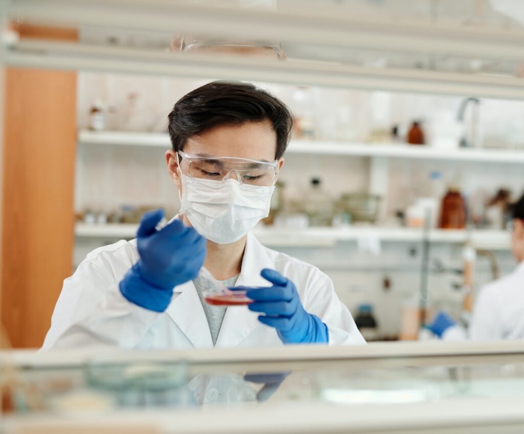 scientist in lab wearing protective gear works in a petri dish