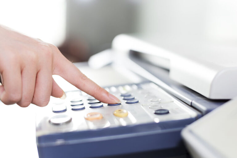 female hand pushing numbers on a fax machine