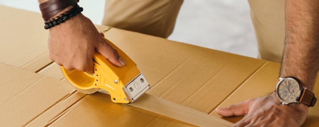 Man taping a cardboard shipping box closed